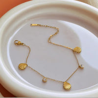 Gold shell charm bracelet on dish