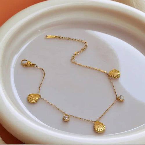 Gold shell charm bracelet on dish